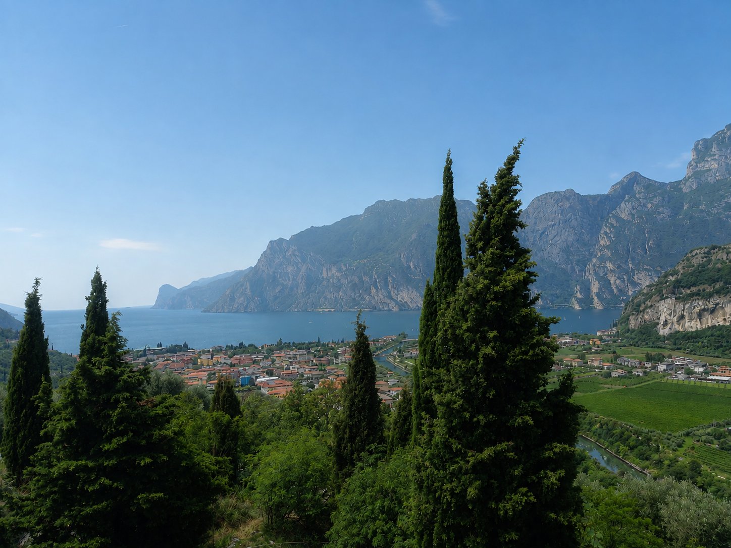 Blick durch Zypressen auf Torbole und den Gardasee